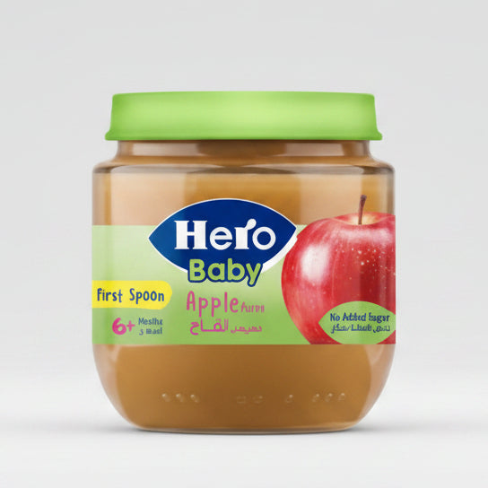 A jar of Hero Baby apple puree with a green lid, featuring a label with a blue Hero Baby logo and an illustration of a red apple.
