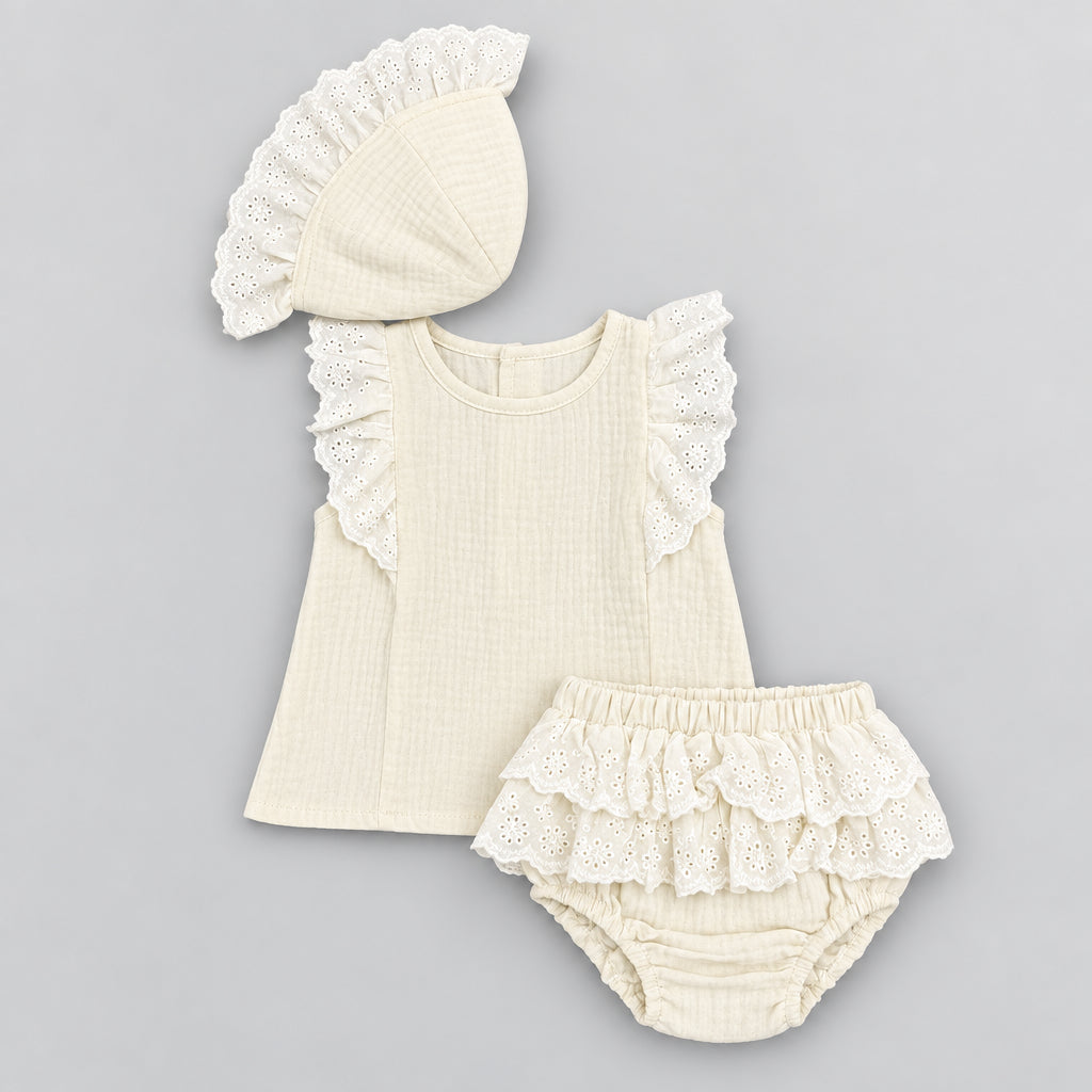 A baby clothing set laid flat on a gray textured background, including a cream-colored sleeveless top with lace ruffle trim, matching bloomers, and a bonnet. White tags are attached, and text in the upper right reads 'Z-2181-4#, 3m-18m, 10pcs in pack'.