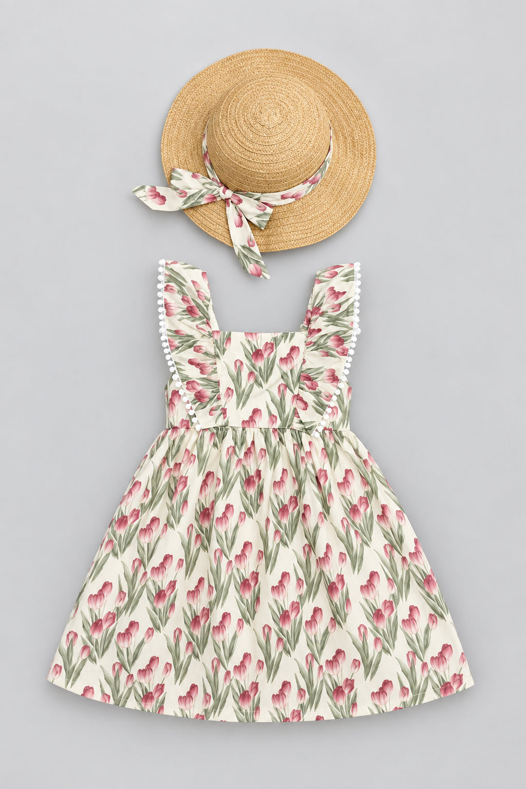 A baby girl's summer outfit set featuring a sleeveless floral dress and a matching straw sun hat with a fabric bow. The dress has a cream background with a pink tulip pattern and green leaves.