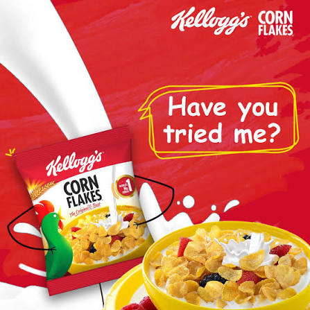 Kellogg's Corn Flakes cereal package shown on a red promotional background with milk splash graphics, alongside a bowl of cereal with milk and fruit. Visible brand text includes Kellogg's and Corn Flakes.