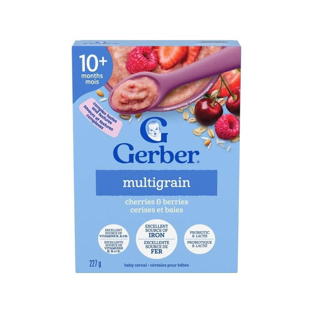 A box of Gerber Multigrain baby cereal in cherries and berries flavor, 227g. The packaging is light blue with a purple spoon graphic showing the cereal, and illustrations of cherries and raspberries.